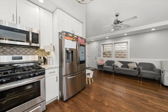 a kitchen with stainless steel appliances a stove a refrigerator and a couch