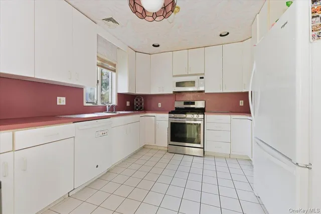 a kitchen with white cabinets a sink and white appliances