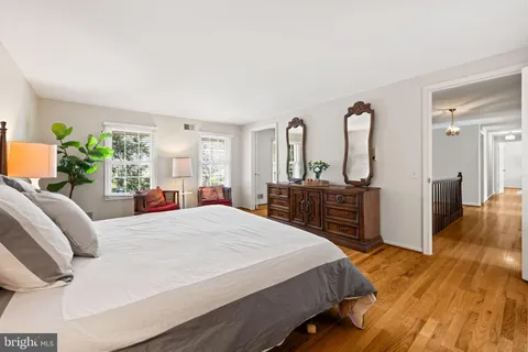 a bedroom with a bed and a dresser with wooden floor