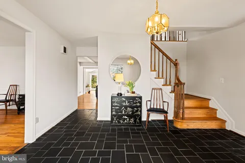 a view of a hallway with wooden floor and a chandelier