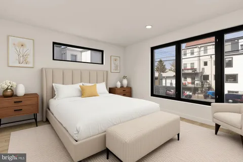 a bedroom with a bed couch and a large window