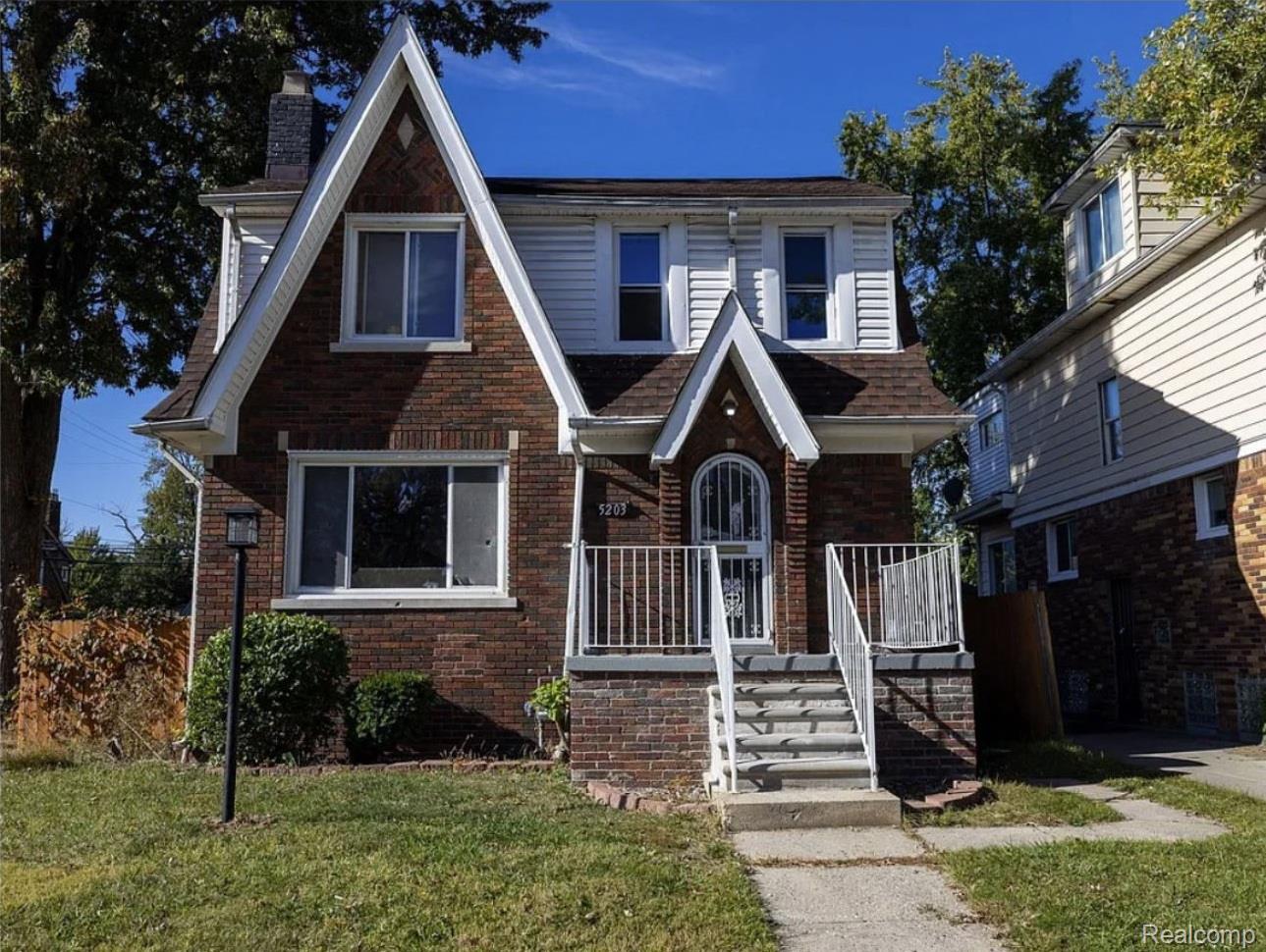5203 Devonshire Road Detroit, MI 48224 - Photo 1 of 16 Brick and siding exterior with a prominent gabled roofline, front porch with railings, and established landscaping
