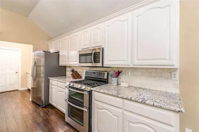 a kitchen with stainless steel appliances granite countertop a stove a refrigerator and a microwave