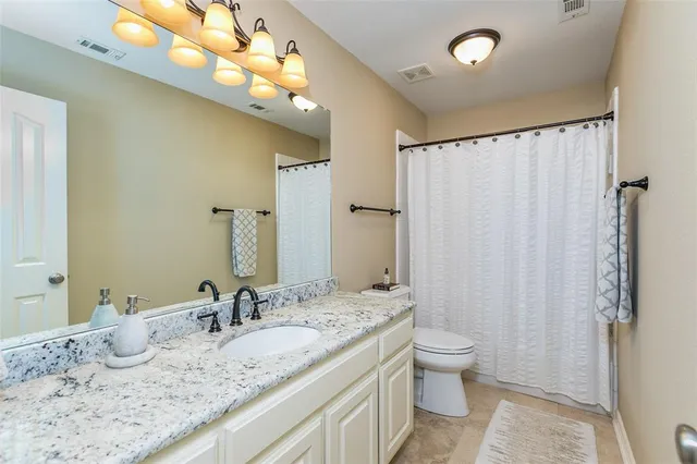 a bathroom with a granite countertop sink a toilet and a large mirror