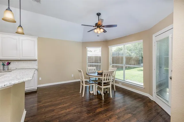 a dining room with wooden floor a chandelier a wooden table and chairs