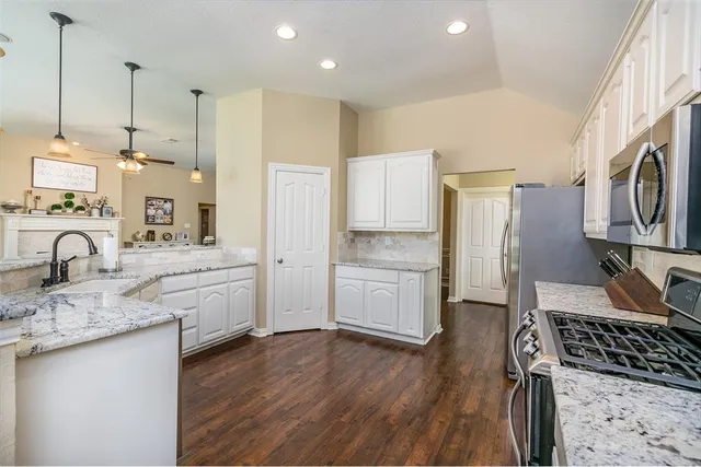 a kitchen with white cabinets and appliances