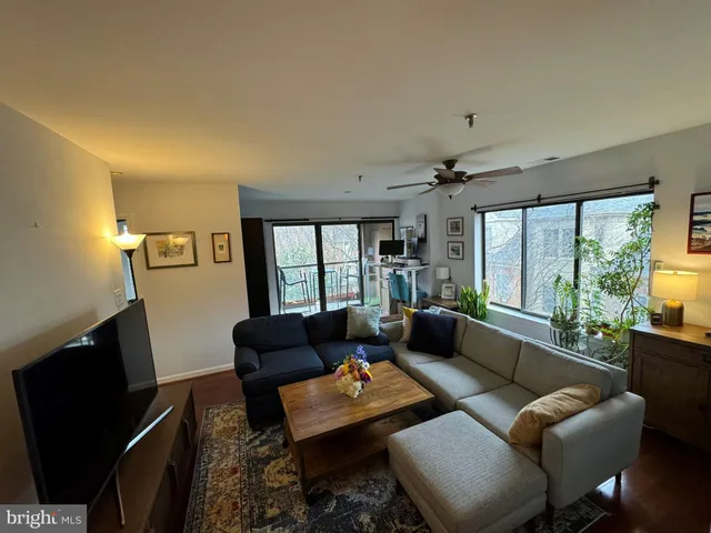a living room with furniture a flat screen tv and a large window