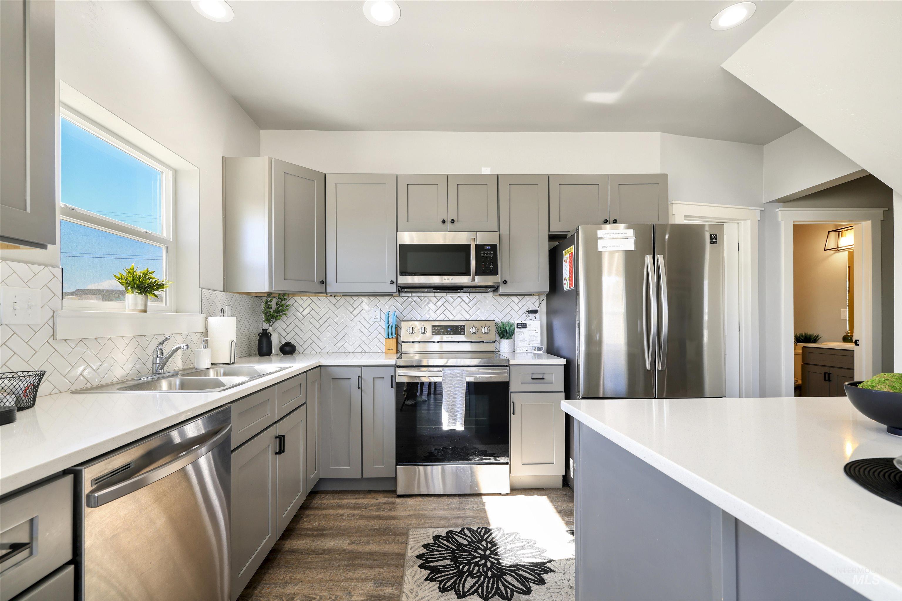 893-899 Shadowleaf Avenue Twin Falls, ID 83301 - Photo 23 of 50 Kitchen featuring stainless steel appliances, gray cabinetry, dark wood-style flooring, recessed lighting, and backsplash