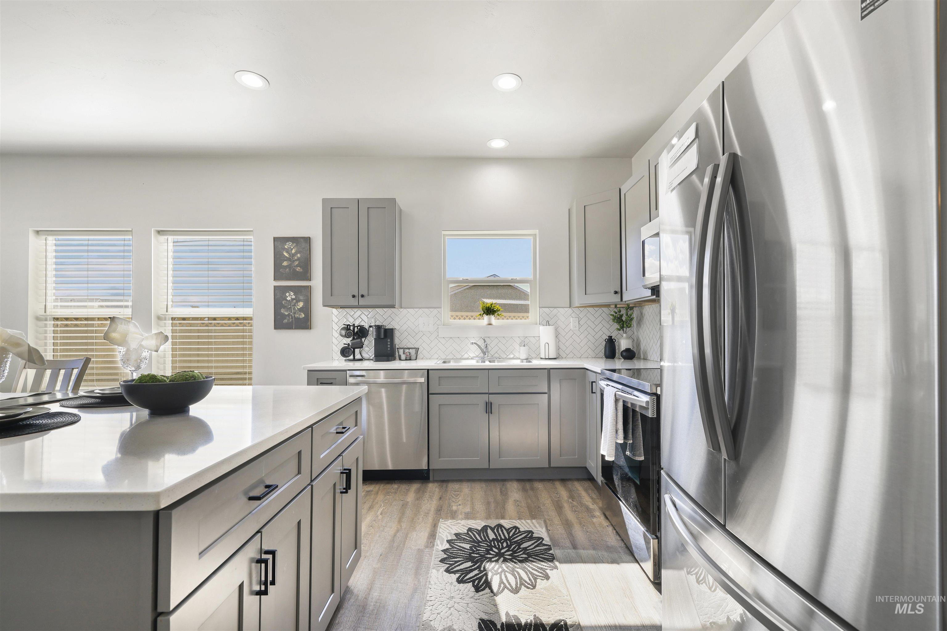 893-899 Shadowleaf Avenue Twin Falls, ID 83301 - Photo 25 of 50 Kitchen with stainless steel appliances, gray cabinets, light wood-style floors, backsplash, and light stone countertops