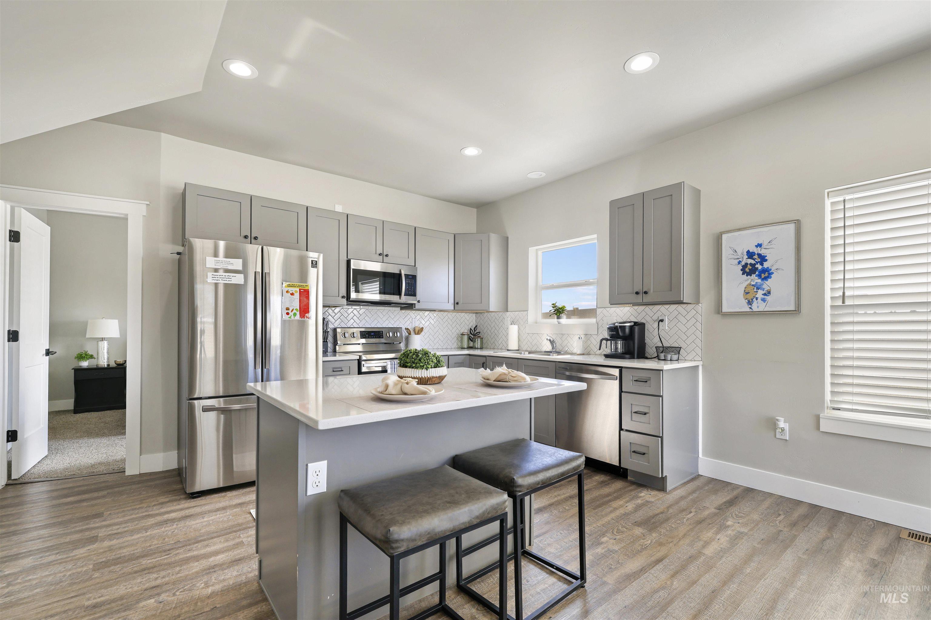 893-899 Shadowleaf Avenue Twin Falls, ID 83301 - Photo 6 of 50 Kitchen with gray cabinets, stainless steel appliances, a breakfast bar area, dark wood-style floors, and recessed lighting