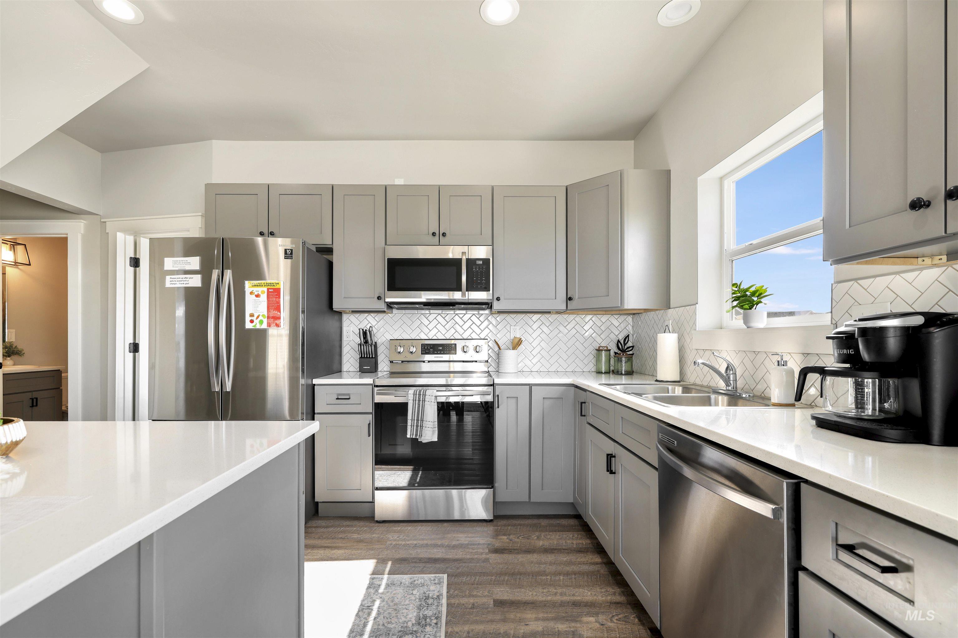893-899 Shadowleaf Avenue Twin Falls, ID 83301 - Photo 7 of 50 Kitchen with gray cabinetry, stainless steel appliances, tasteful backsplash, dark wood-style floors, and recessed lighting