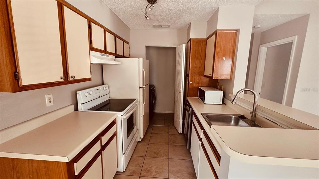 1087 South Hiawassee Road, Unit 422 Orlando, FL 32835 - Photo 13 of 17 a kitchen with a sink a stove and a refrigerator