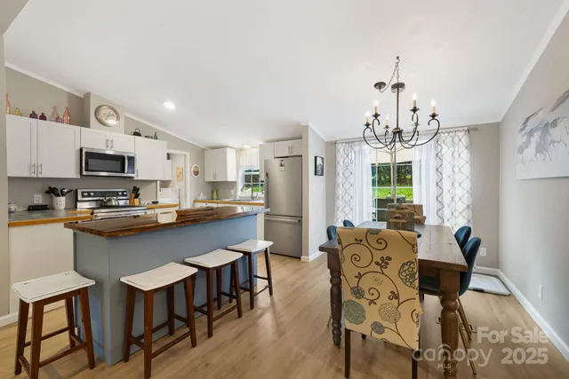 a kitchen with stainless steel appliances a dining table chairs microwave and sink