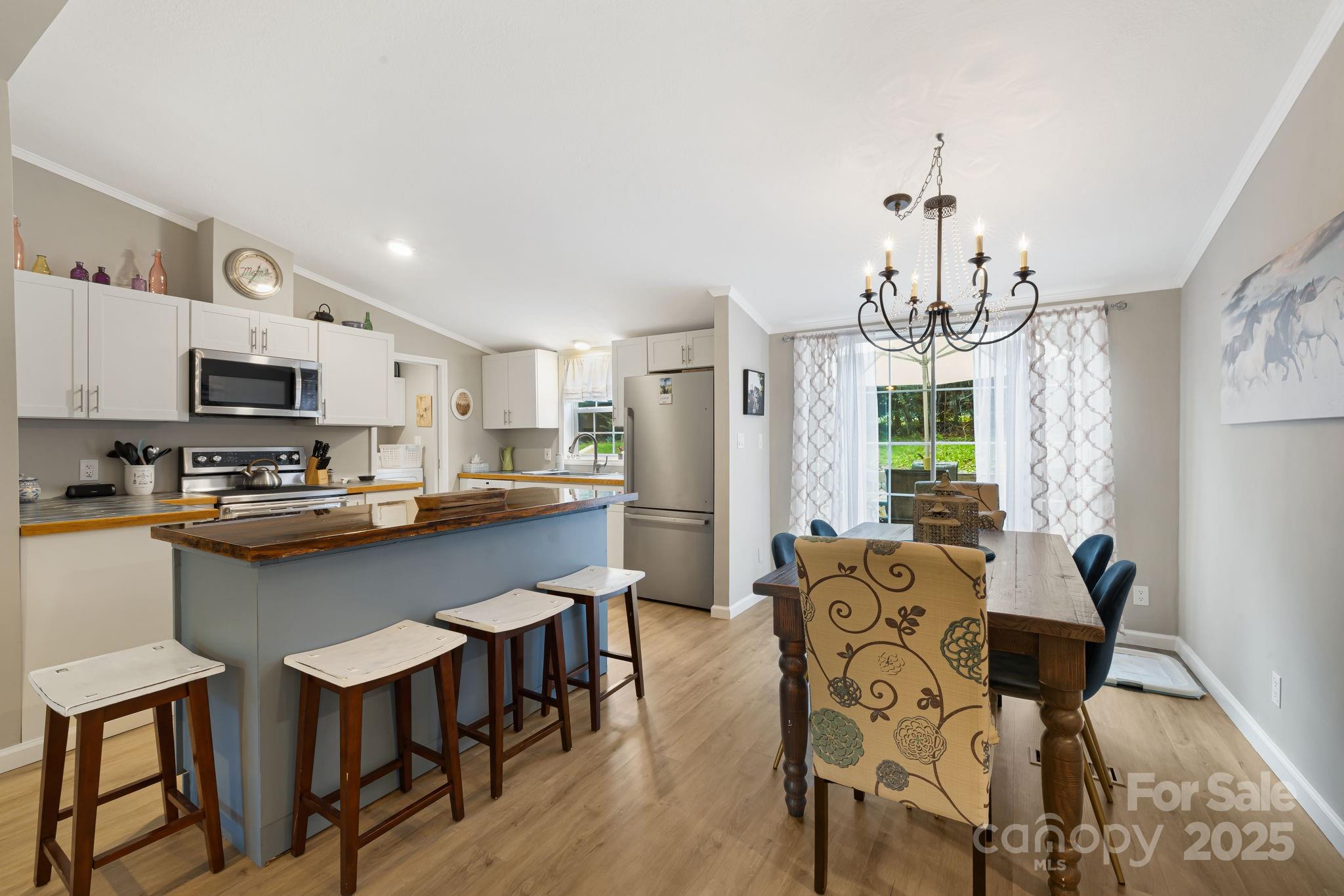 a kitchen with stainless steel appliances a dining table chairs microwave and sink
