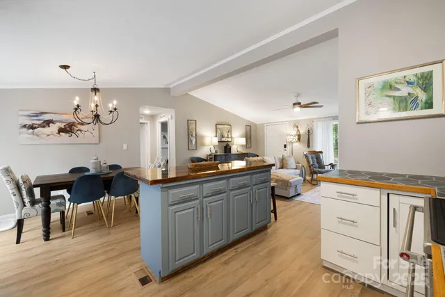 a kitchen with a sink dishwasher a dining table and chairs with wooden floor
