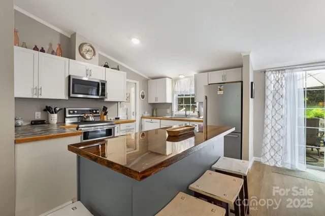 a kitchen with stainless steel appliances granite countertop a refrigerator a stove a sink a dining table and chairs with wooden floor