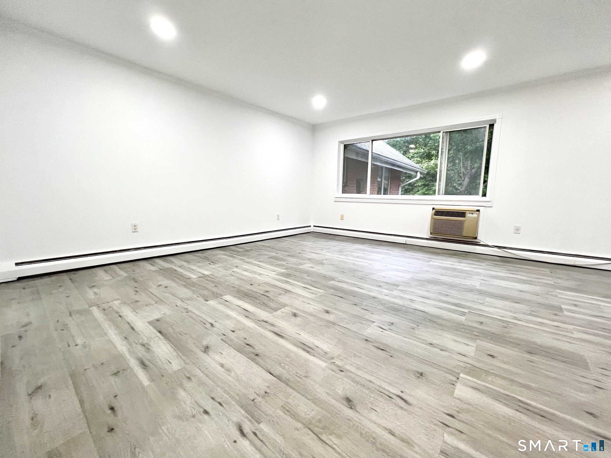 208 Flax Hill Road, Unit 32 Norwalk, CT 06854 - Photo 7 of 12 an empty room with wooden floor and windows