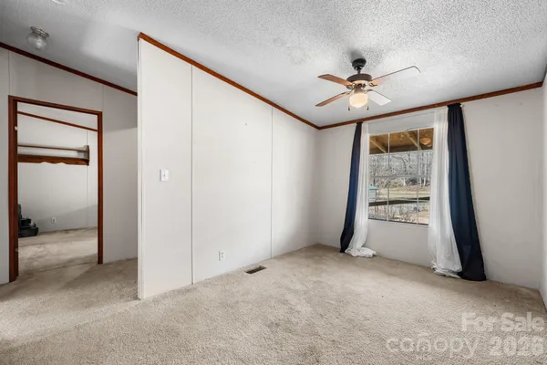 an empty room with windows and fan