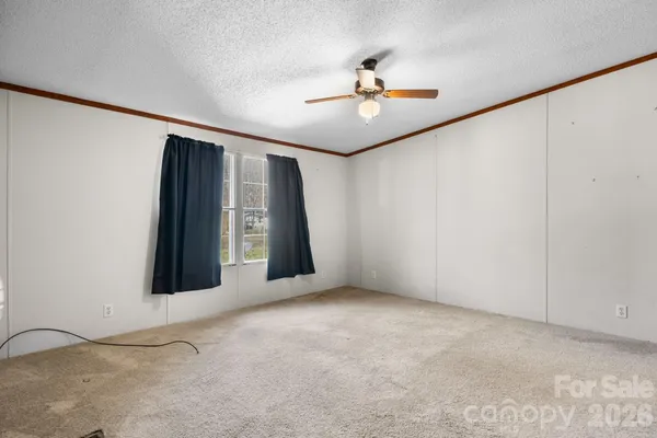 a view of an empty room with window and chandelier fan
