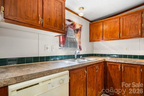 a kitchen with granite countertop stainless steel appliances a sink dishwasher and cabinets with wooden floor