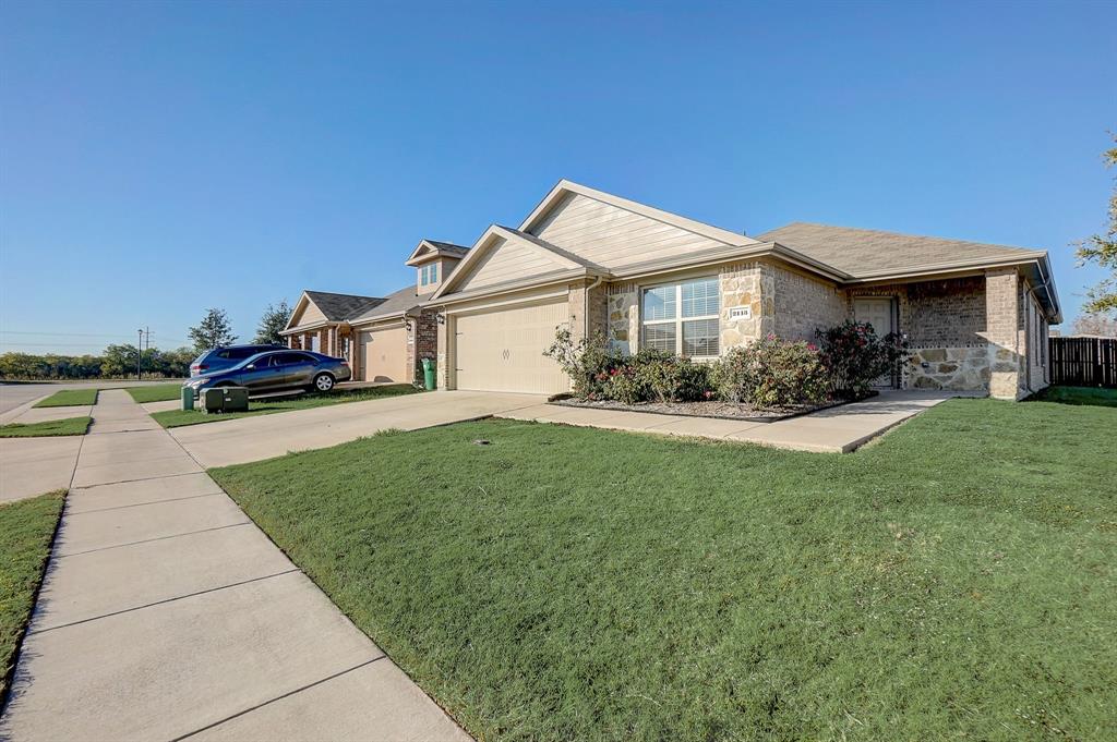 View of front facade featuring driveway, stone siding, and a garage