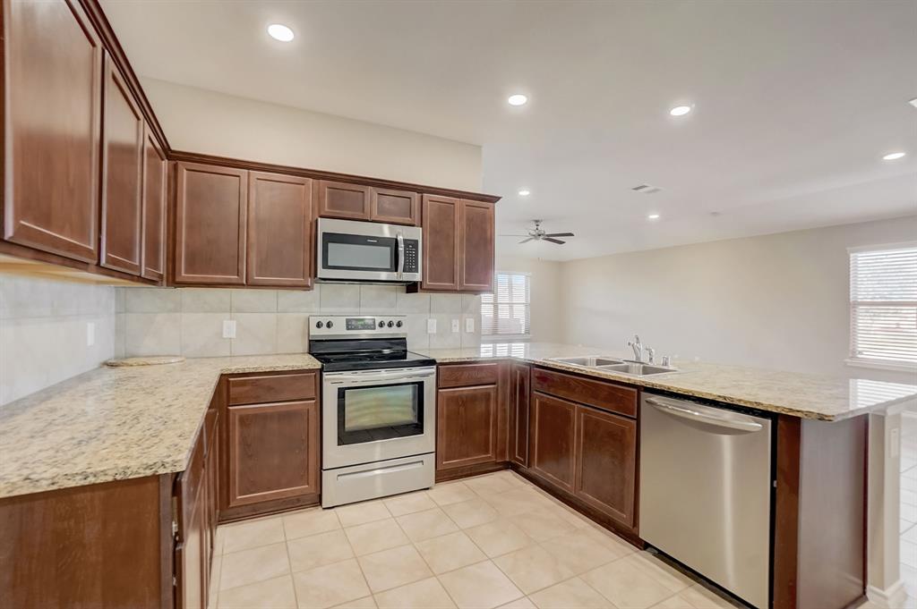 2113 Rubin Road Fate, TX 75189 - Photo 7 of 37 Kitchen featuring stainless steel appliances, tasteful backsplash, a peninsula, recessed lighting, and light stone countertops