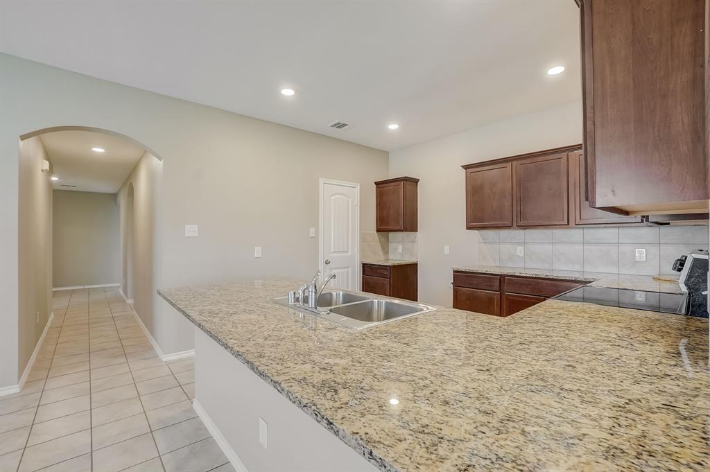 2113 Rubin Road Fate, TX 75189 - Photo 8 of 37 Kitchen with arched walkways, tasteful backsplash, a peninsula, light tile patterned flooring, and electric range