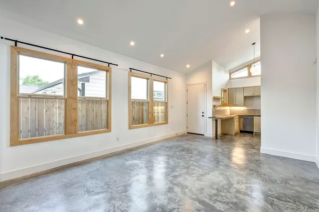a view of a room with a large window and kitchen view