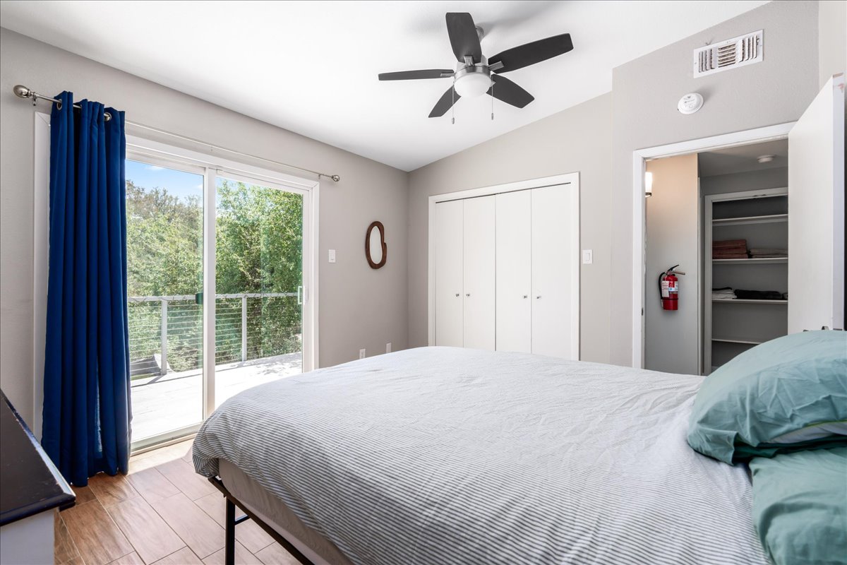207 Rogers Ridge Street San Marcos, TX 78666 - Photo 17 of 35 A bright secondary bedroom welcomes abundant natural light through a large picture window, complemented by warm wood flooring & a generous closet for comfort & convenience.