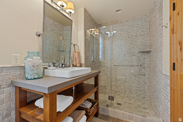 105 River Bend Circle, Unit 105 Springdale, UT 84767 - Photo 26 of 56 Contemporary bathroom featuring a glass-enclosed shower with mosaic tile surround, a vessel sink on a wood-finish vanity with open shelving, and a chrome faucet