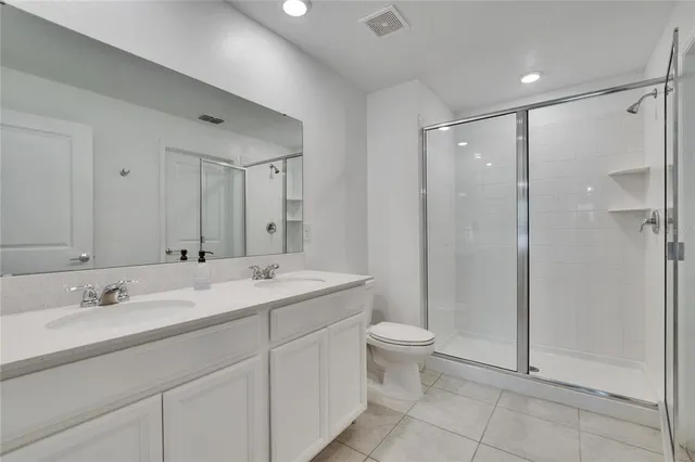 a bathroom with a double vanity sink toilet and shower