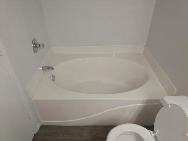 a bathroom with a toilet and white bath tub