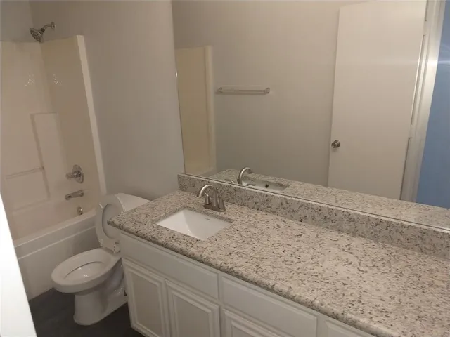 a bathroom with a granite countertop sink a toilet and bathtub