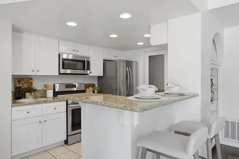 a kitchen with kitchen island granite countertop a sink stove and refrigerator