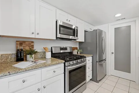 a kitchen with granite countertop a sink stove and refrigerator