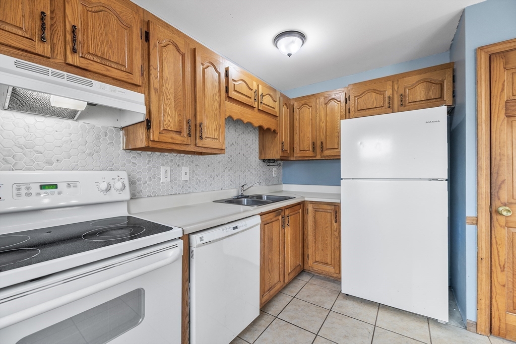 22 Pleasant Street, Unit D Lawrence, MA 01841 - Photo 9 of 32 a kitchen with a refrigerator sink and cabinets