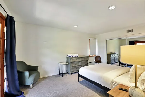 a bedroom with a bed and a lamp on dresser