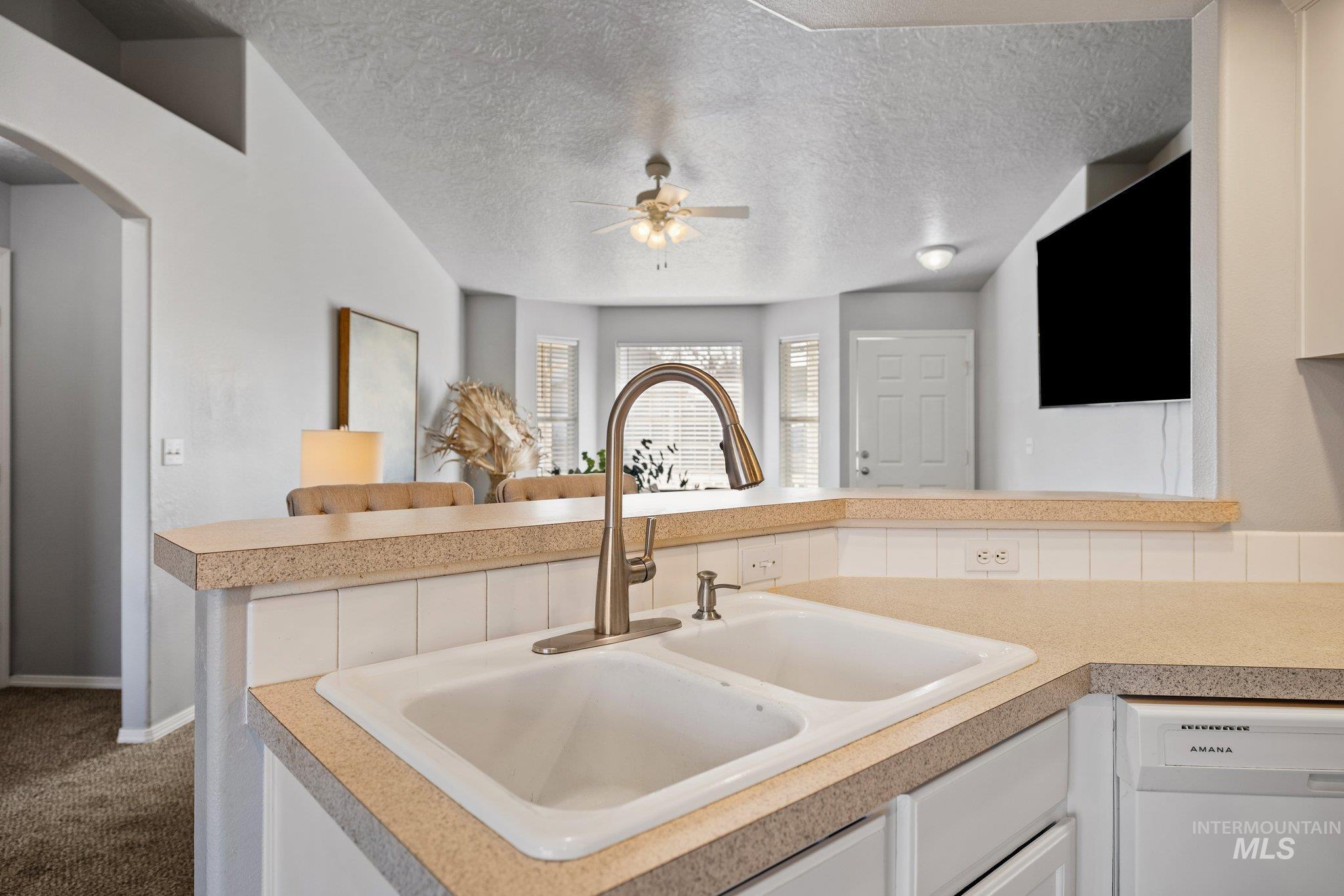 14250 Blue Ridge Street Caldwell, ID 83607 - Photo 14 of 33 Kitchen with white dishwasher, light countertops, white cabinetry, arched walkways, and a textured ceiling