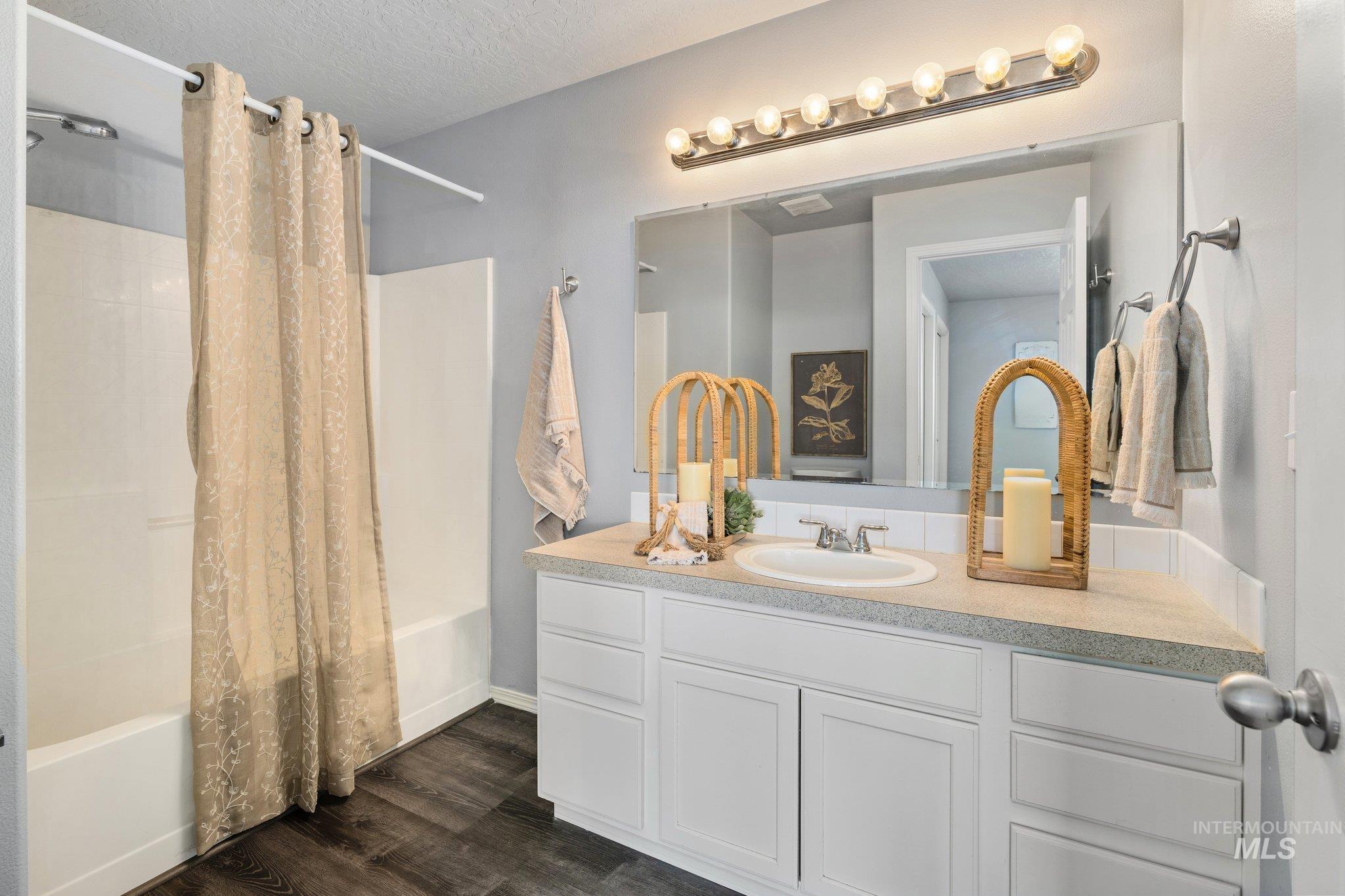 14250 Blue Ridge Street Caldwell, ID 83607 - Photo 19 of 33 Full bath featuring shower / bath combo with shower curtain, vanity, dark wood-style floors, and a textured ceiling