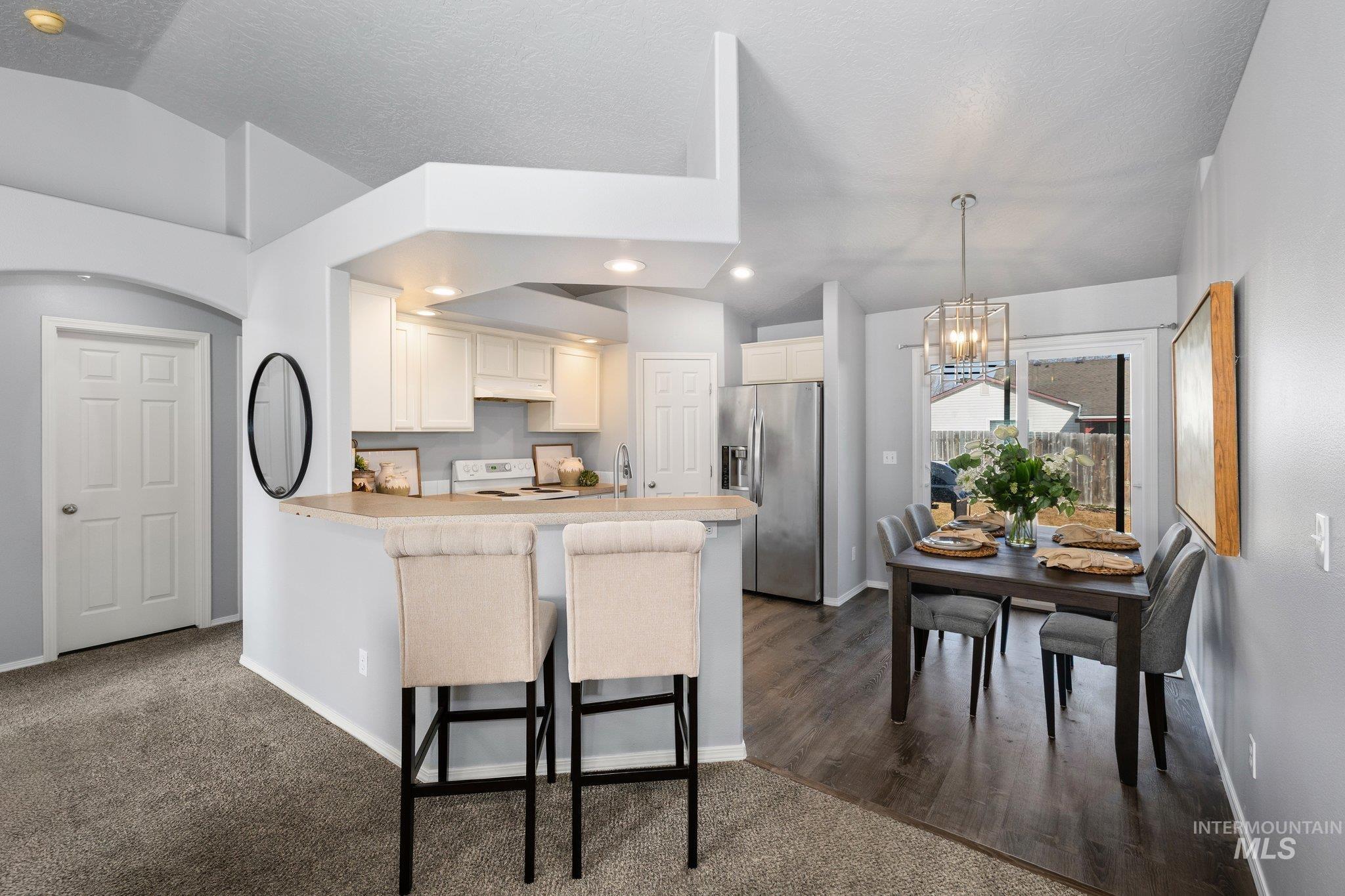 14250 Blue Ridge Street Caldwell, ID 83607 - Photo 8 of 33 Kitchen with stainless steel refrigerator with ice dispenser, hanging lights, light countertops, a breakfast bar area, and white electric stove