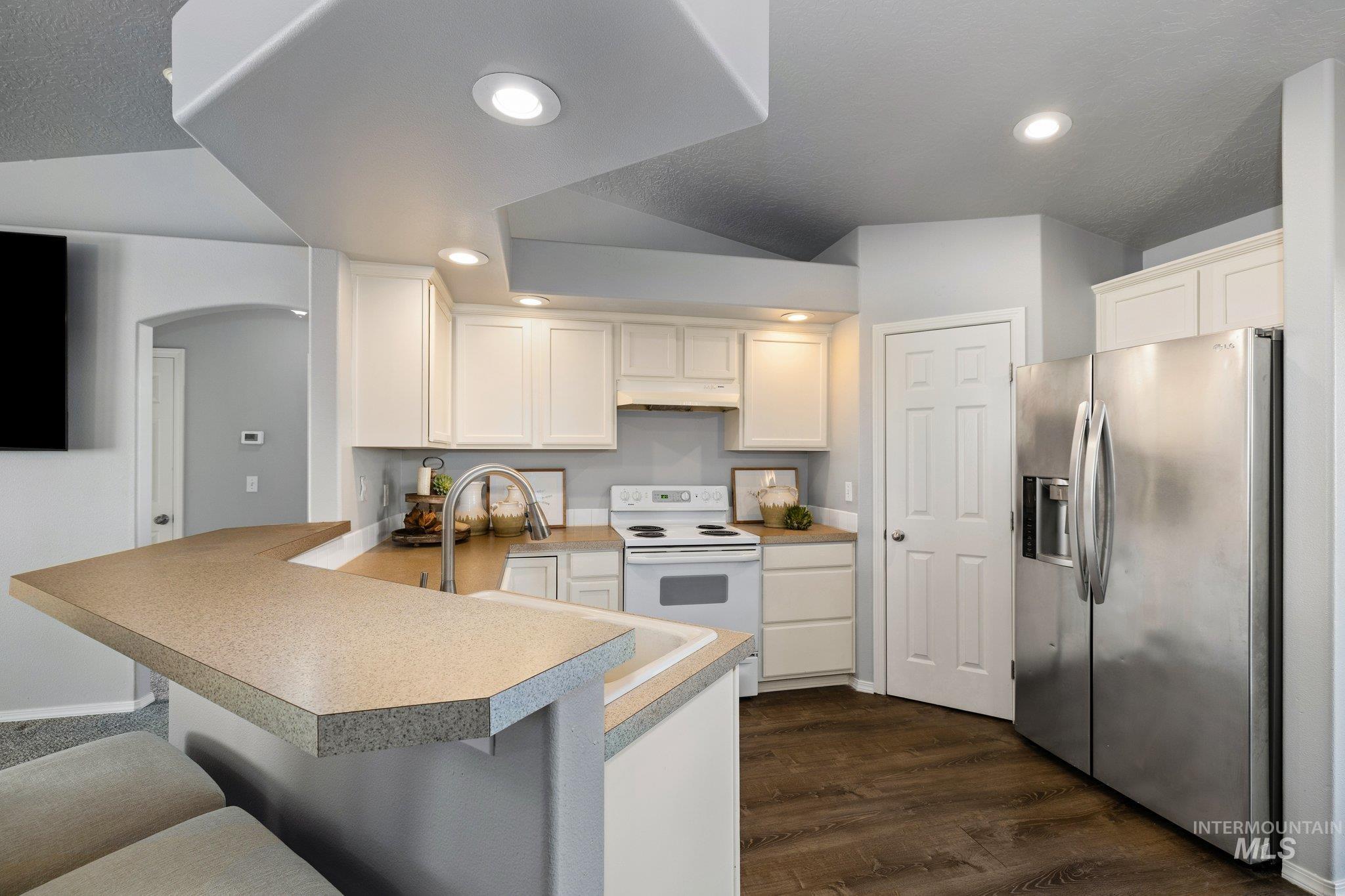 14250 Blue Ridge Street Caldwell, ID 83607 - Photo 9 of 33 Kitchen featuring stainless steel refrigerator with ice dispenser, white electric range, a peninsula, white cabinets, and recessed lighting