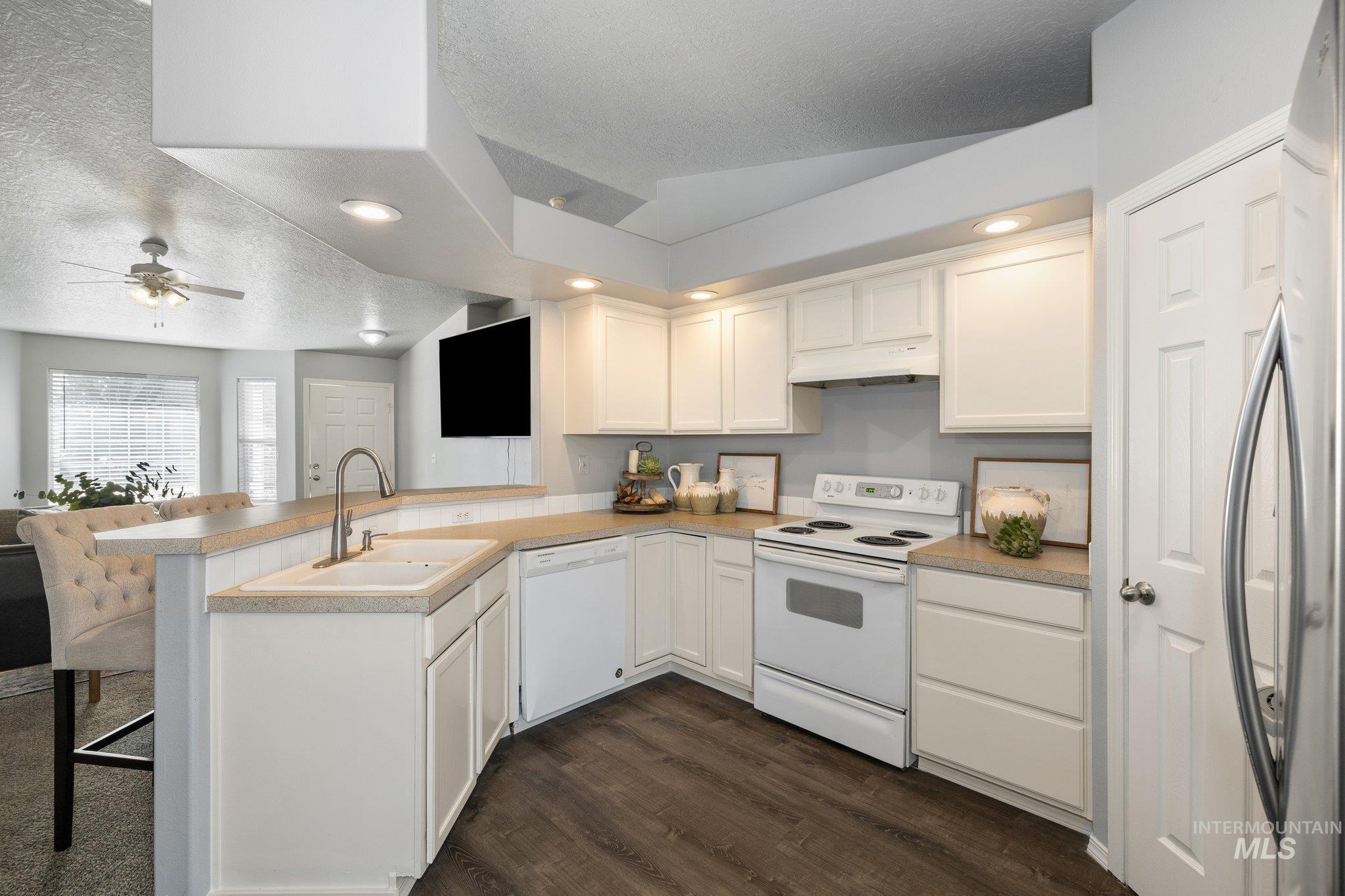 14250 Blue Ridge Street Caldwell, ID 83607 - Photo 10 of 33 Kitchen featuring white appliances, a peninsula, white cabinets, dark wood-style floors, and recessed lighting