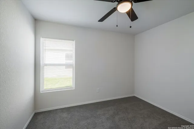 an empty room with a window and a fan
