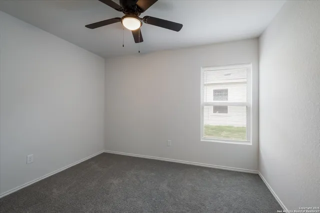 an empty room with a window and a fan