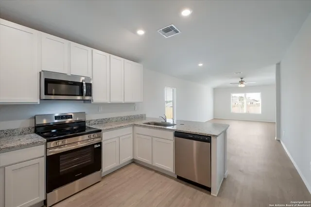 a kitchen with granite countertop white cabinets and stainless steel appliances