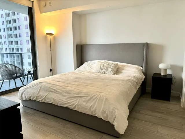 a large bed sitting in a bedroom next to a lamp and a large window