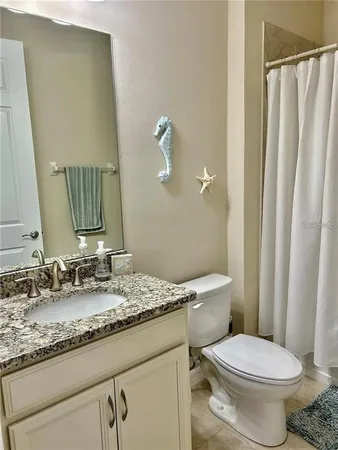 a bathroom with a granite countertop toilet sink and mirror
