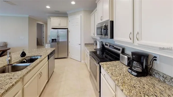 a kitchen with granite countertop a sink a stove and refrigerator