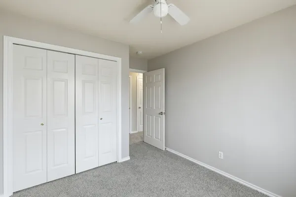 a view of an empty room and chandelier fan