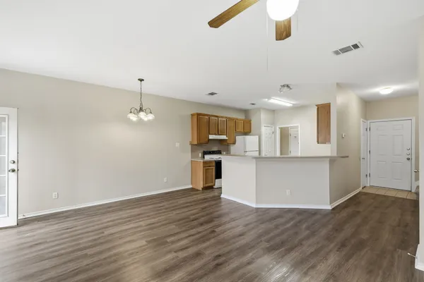a view of kitchen and empty room with wooden floor